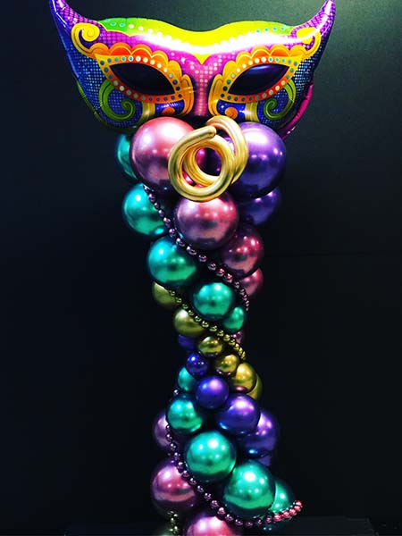This 7 foot tall column is created from metalic sheen balloons and is topped with a mylar Mardi Gras / Carnevale mask.