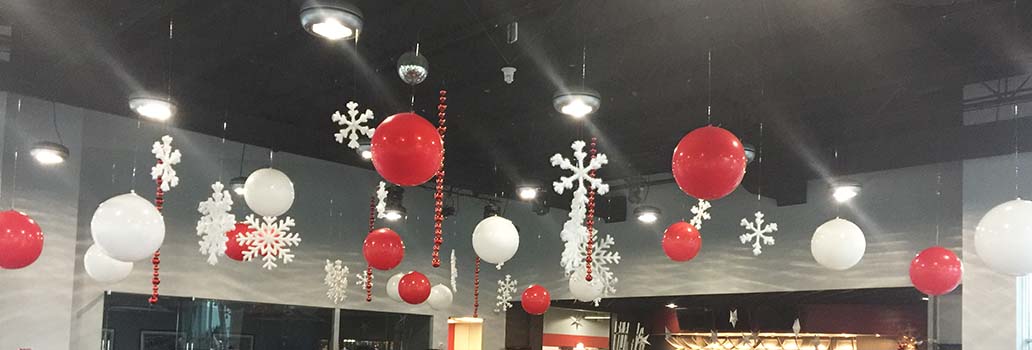 A ceiling decorated with suspended white and red 30 inch diameter balloons and snowflakes