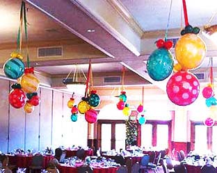 Clusters of Balloonatics 24 inch diameter Christmas decoration balls are encased in clear long-lasting mylar balloons and serve as an excellent holiday party ceiling decoration