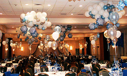 The ceiling of this holiday party room is covered with whaite and silver balloon clouds and mylay balloon snowflakes