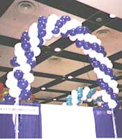 Swirled balloon arches over a trade show booth improve regonition