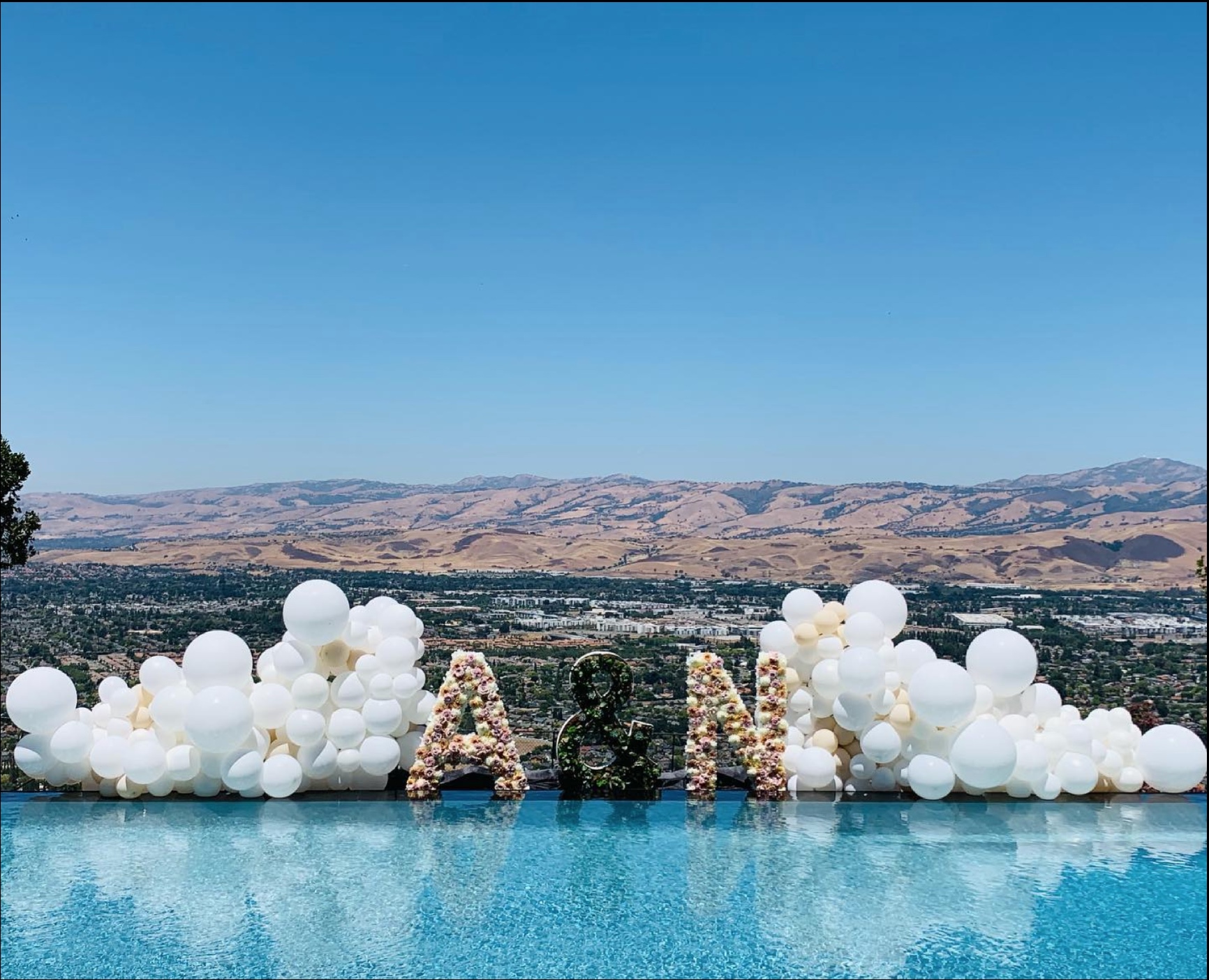 An 30 foot wide organic style decoration in white latex balloons celebrating a wedding.