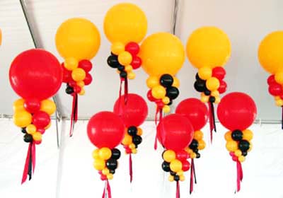 Giant 30 inch red and goldenrod helium filled balloons with tiered collar balloons placed to visually unify decor in a large tent venue