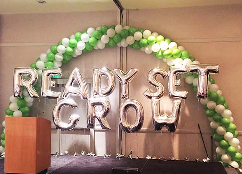 A spiral packed 30 foot balloon arch with mylar lettrs expressing the theme of a corporate meeting
