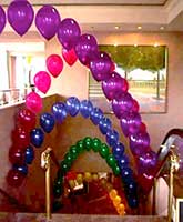 These string-of-pearls syyle balloon arches float over an escalator at the San Jose Fairmont Hotel to provide a visual pathway leadin g guests to an event in the ballrooms