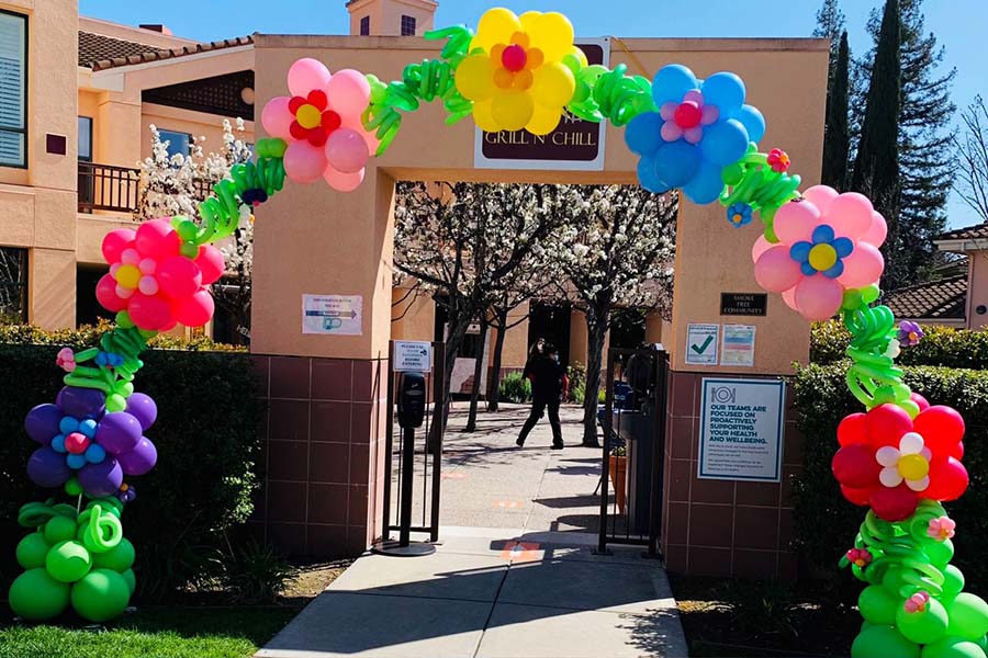 An 30 foot Blossom Style arch of multicolored balloons celebrating the reopening of a Senior Center.