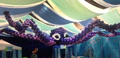 Garlands of quartz purple and lilac latex balloons are used to create a giant octopus suspended from the ceiling for a sea-themed event.