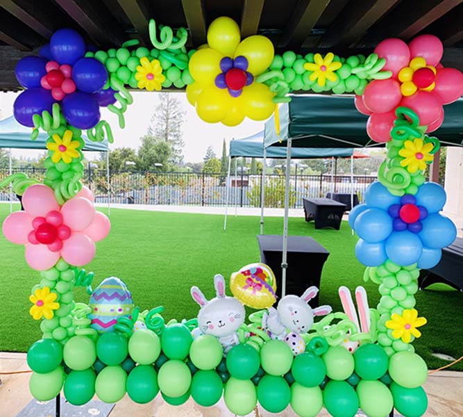 Two easter theme decorations made with mylar and latex balloons on poles placed in the yard of a residence