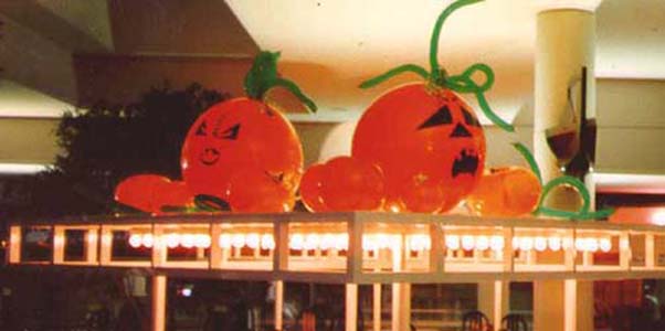 A series of orange 30 inch diameter pumpkin balloons with green vine accents arranged on an elevated surface as a pumpkin patch.