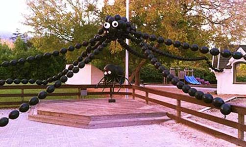 This giant balloon spider sculpture decorates an outdoor play area for a Halloween event.