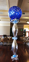 This bubble decoration made of silver mylar vertical balloons with pale blue balloon collars is topped by a large saphire blue balloon with snow flake designs