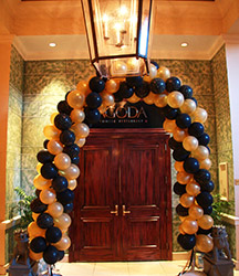 A swirled arch of gold and black balloons frames the entrance to this restaurant with a look of elegance.