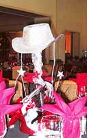 A sparkling silver colored centerpiece consisting of a six gun and western hat for a western theme event