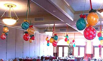 Red and green Holiday Ornament balloons suspended from the ceiling throughout a venue