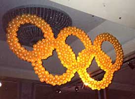 Giant lighted Olympic ring sculpture suspended from the venue ceiling for a corporate competition event