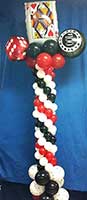 A seven-foot tall column of swirled red, white and black latex balloons topped by a combination of mylar dice and playing card balloons for a casino party