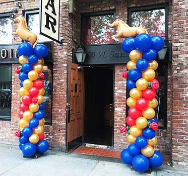 These eight foot tall derby-theme columns are each topped by a mylar stallion.  They flank the entrance to a local pub promoting a Kentucky Derby day theme.