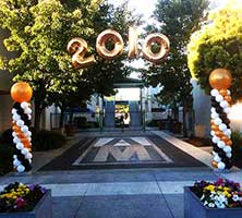 Columns of swirled white, gold, and black balloons topped by giant gold balloons flank the entrance driveway and anchor an arch suspended over the drive for a New Year event