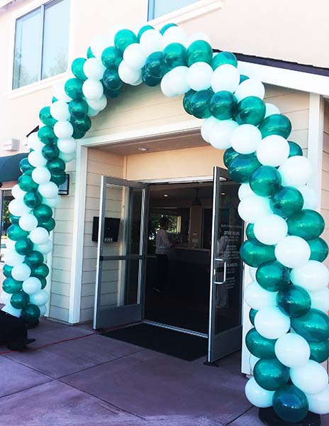 These balloon arches floating over the swimming pool have giant balloon baby pacifiers in the middle for an outdoor baby shower event