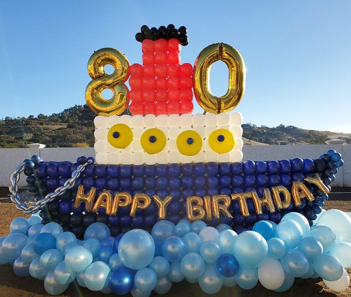 Thi9s 80th birthday celebrant is still sailing strong in a birthday boat balloon sculpture