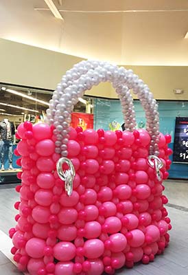 An eight foot tall balloon sculpture opf a handbag for a shopping centere luggage sale promotion
